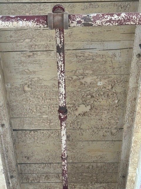 A rusty pipe is hanging from a wooden wall