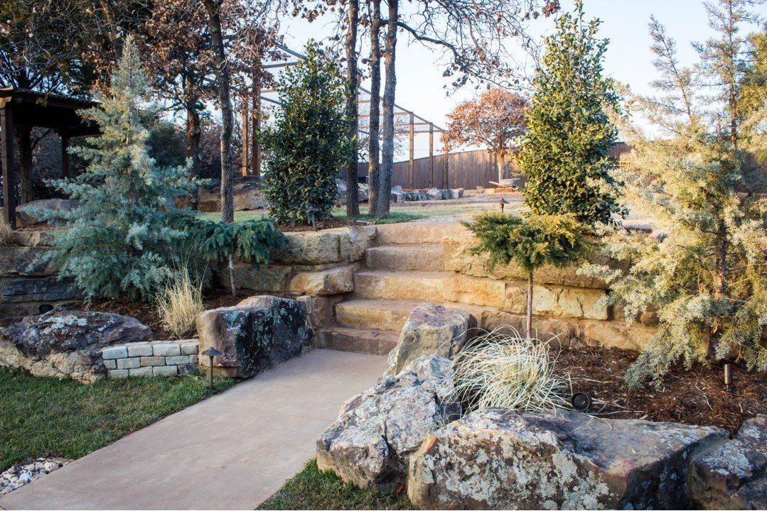 A stone walkway leading up to a set of stairs surrounded by rocks and trees.