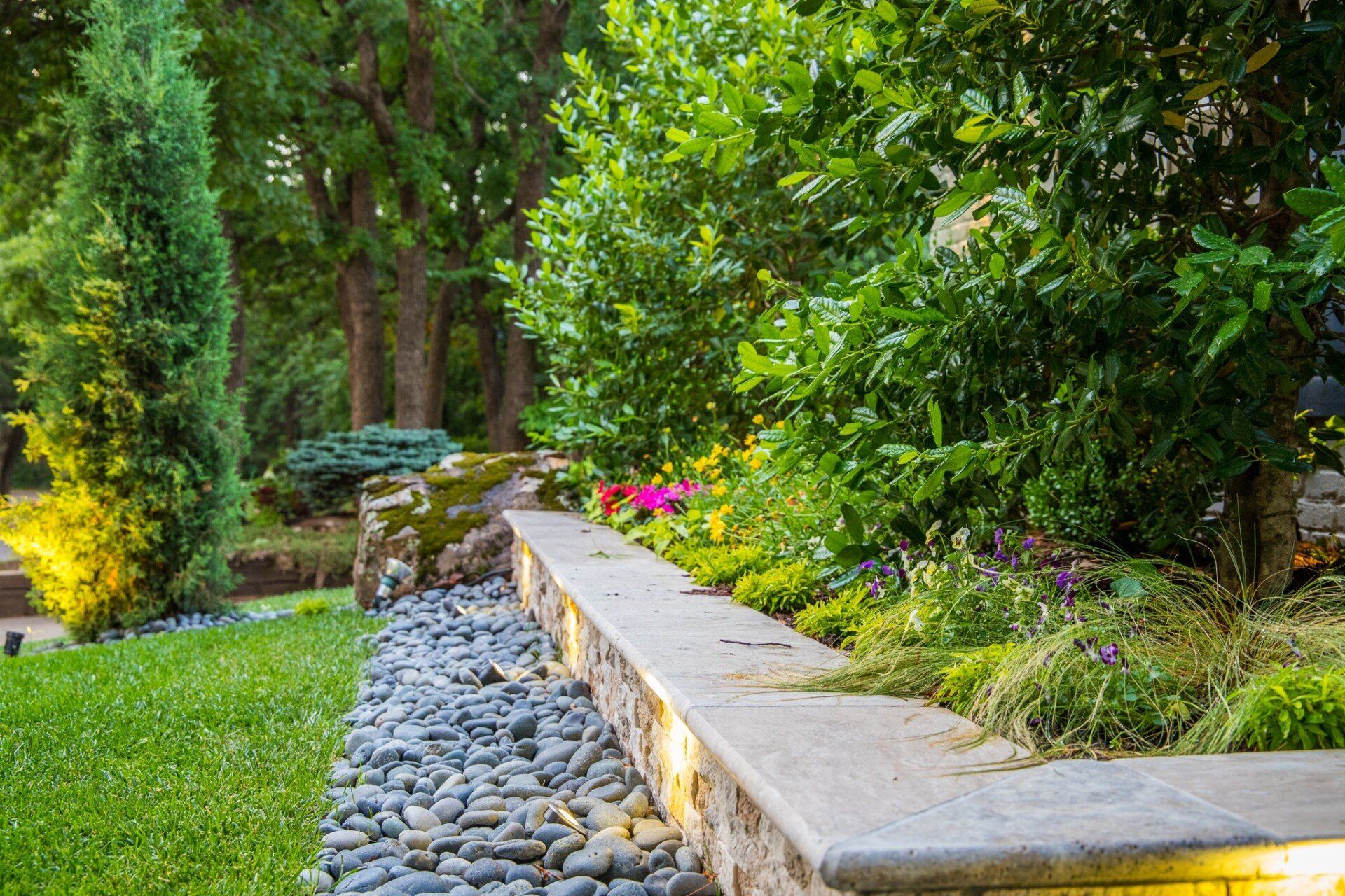 A stone wall surrounded by rocks and flowers in a garden.