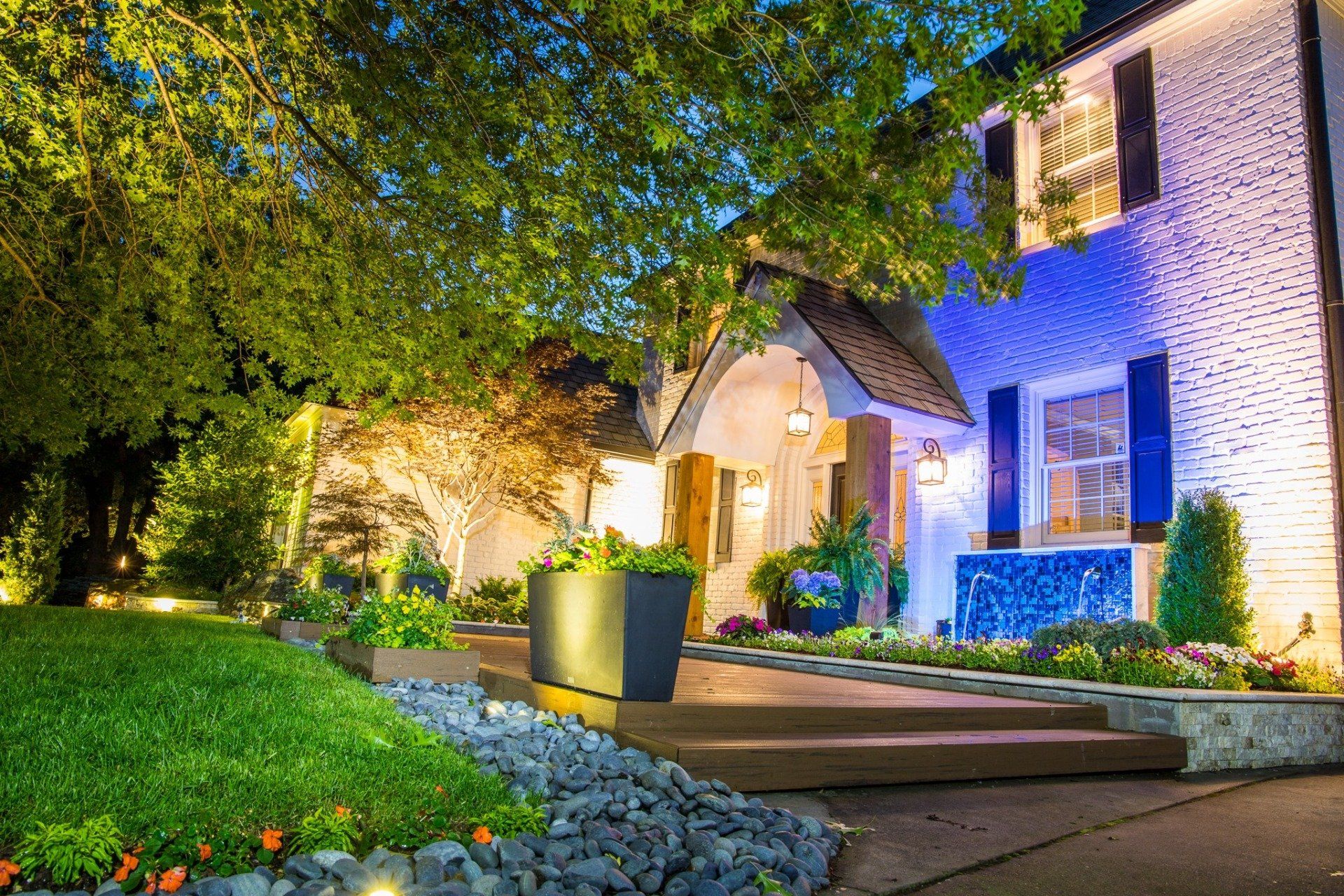 A white brick house with blue shutters is lit up at night.