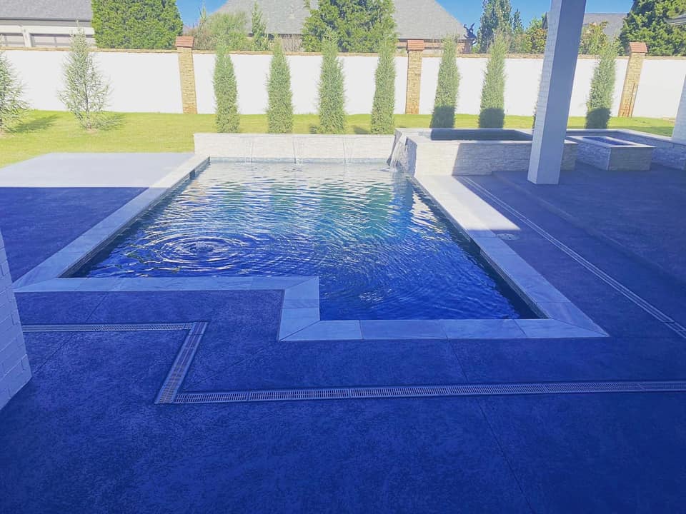 There is a large swimming pool in the backyard of a house.