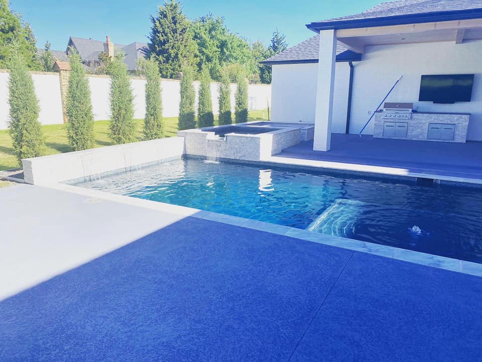 There is a large swimming pool in the backyard of a house.