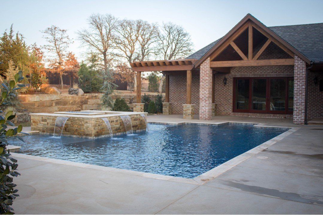 There is a large swimming pool in the backyard of a house.