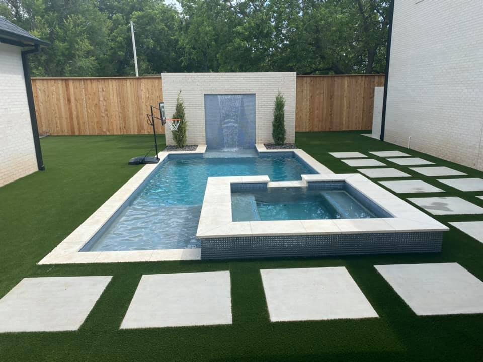 A large swimming pool with a waterfall in the backyard