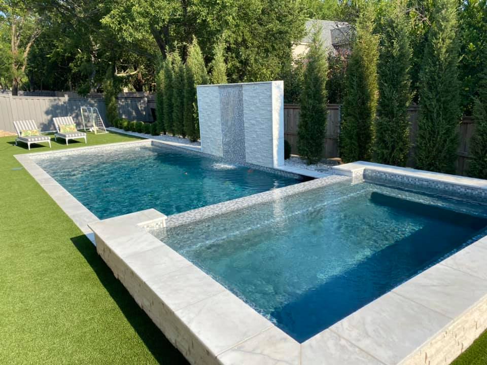 Two swimming pools are sitting next to each other on a lush green lawn.
