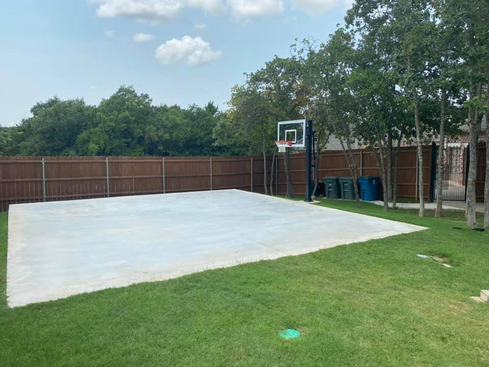 A backyard with a basketball hoop and a fence