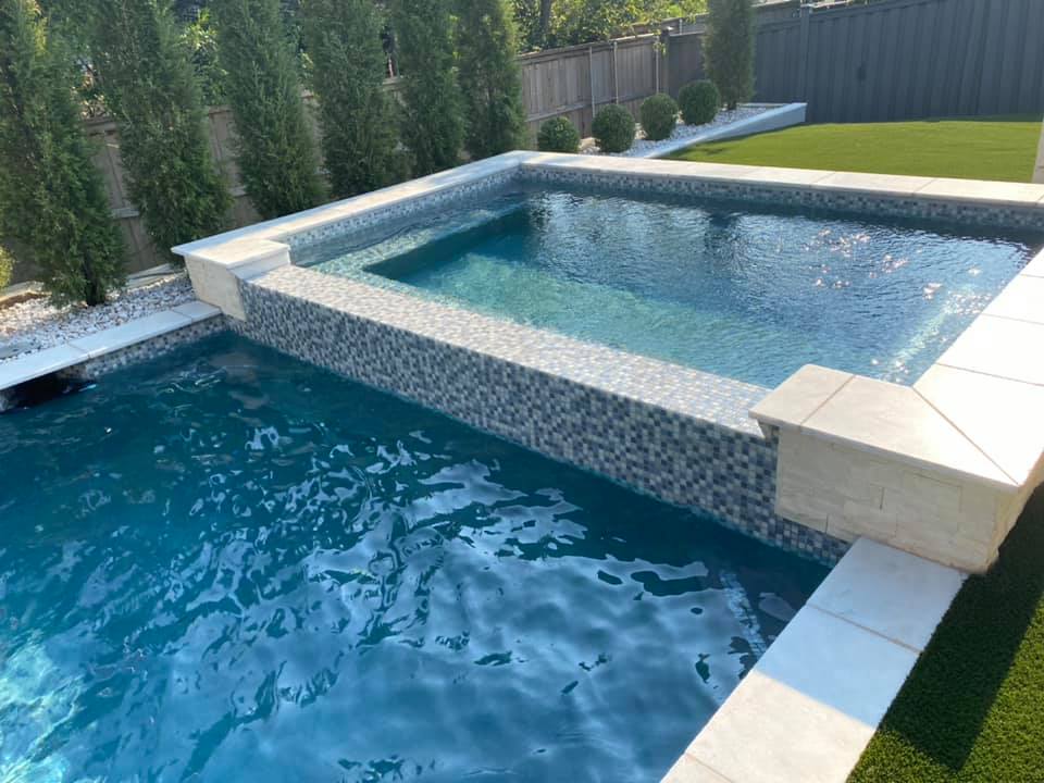 A large swimming pool with a hot tub in the middle of it.