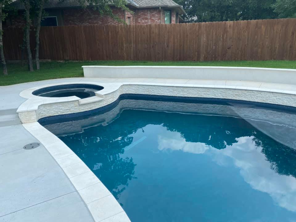 A large swimming pool with a hot tub in the backyard.