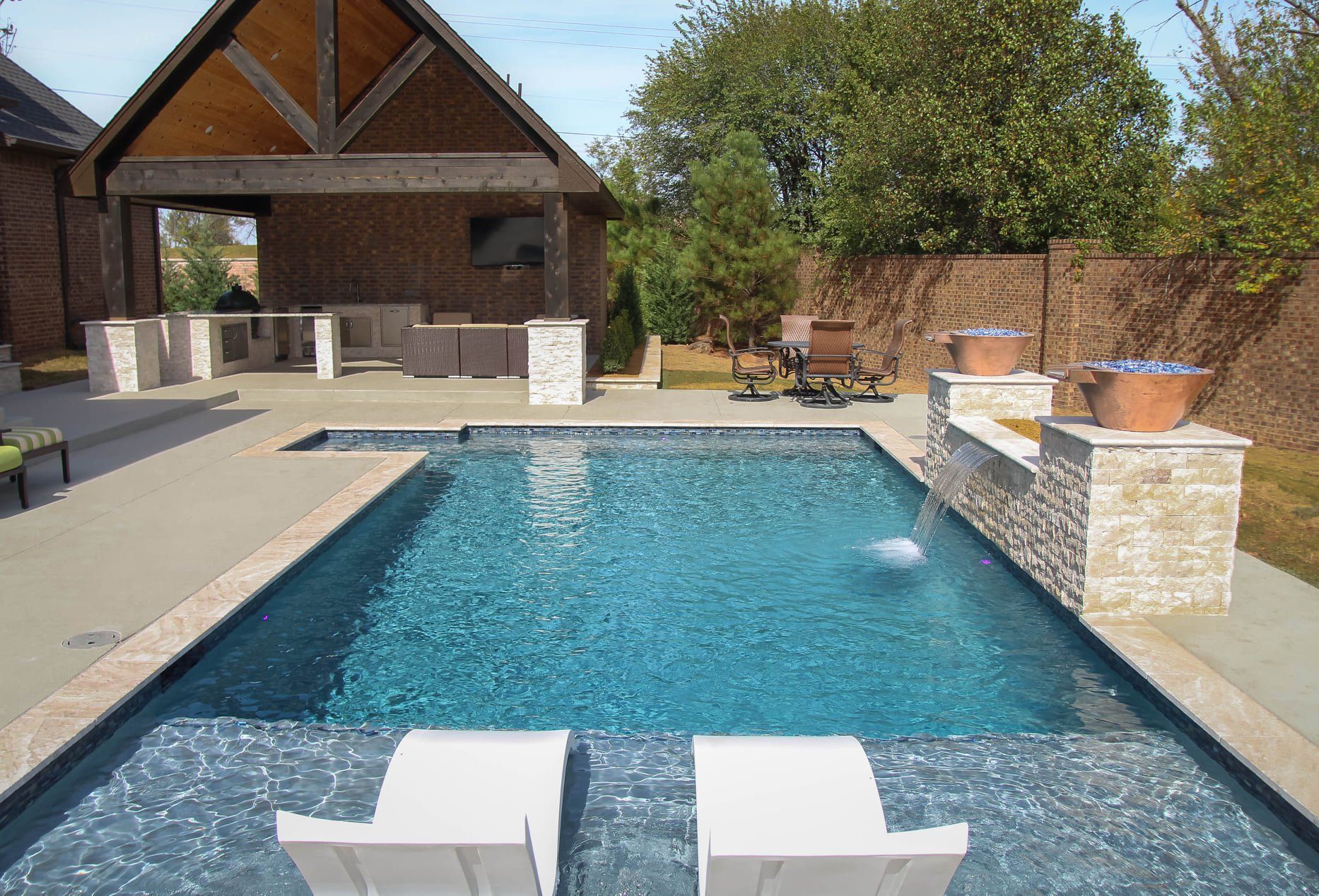 A large swimming pool with two chairs in front of it