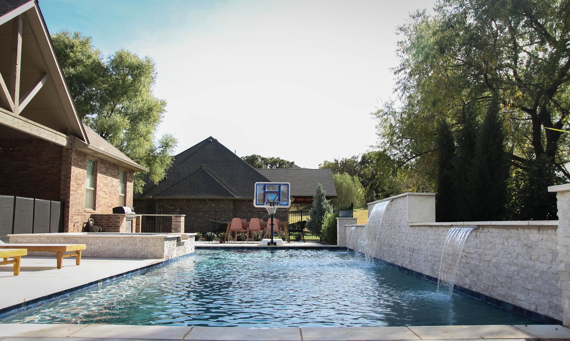 A large swimming pool with a basketball hoop in the backyard