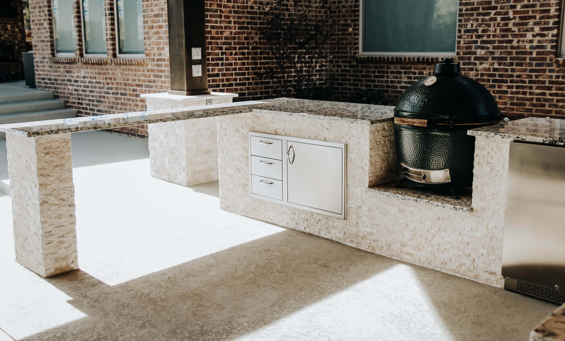 A large grill is sitting on a patio in front of a brick building.