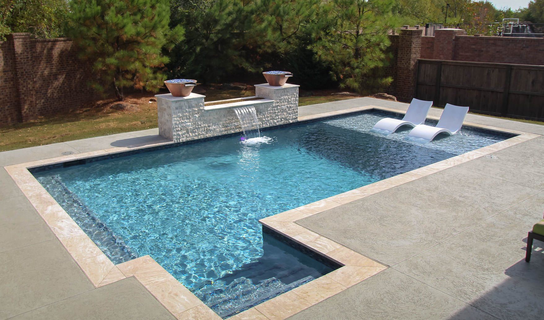 A large swimming pool with two lounge chairs in it