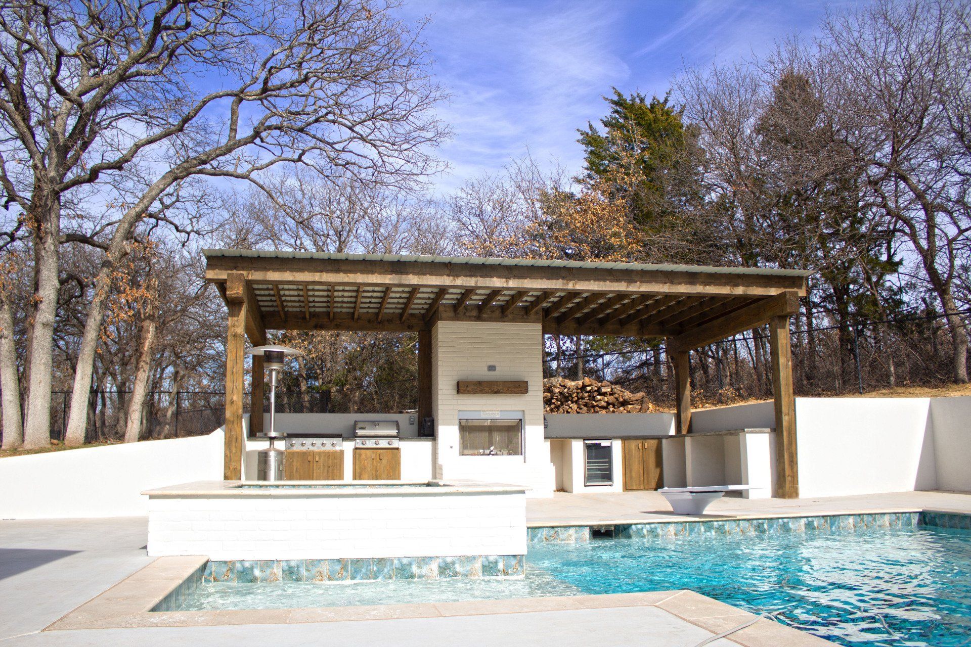 A swimming pool with a kitchen and a pergola over it