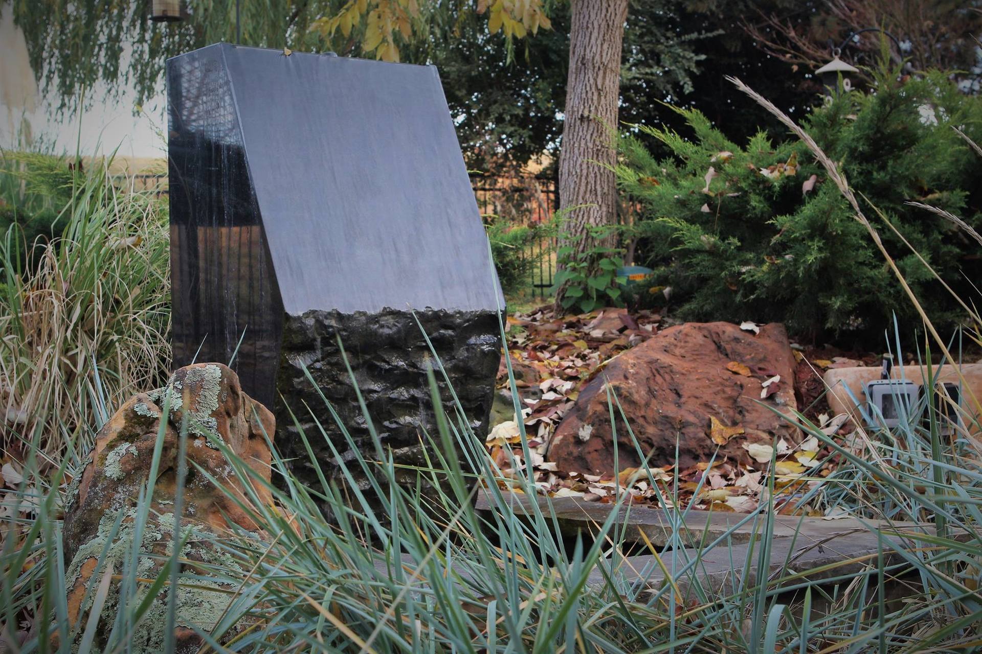 A black cube is sitting in the middle of a grassy field.