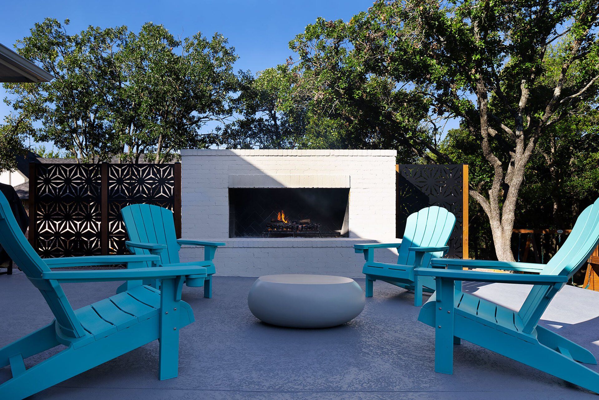 A patio with blue chairs and a fireplace