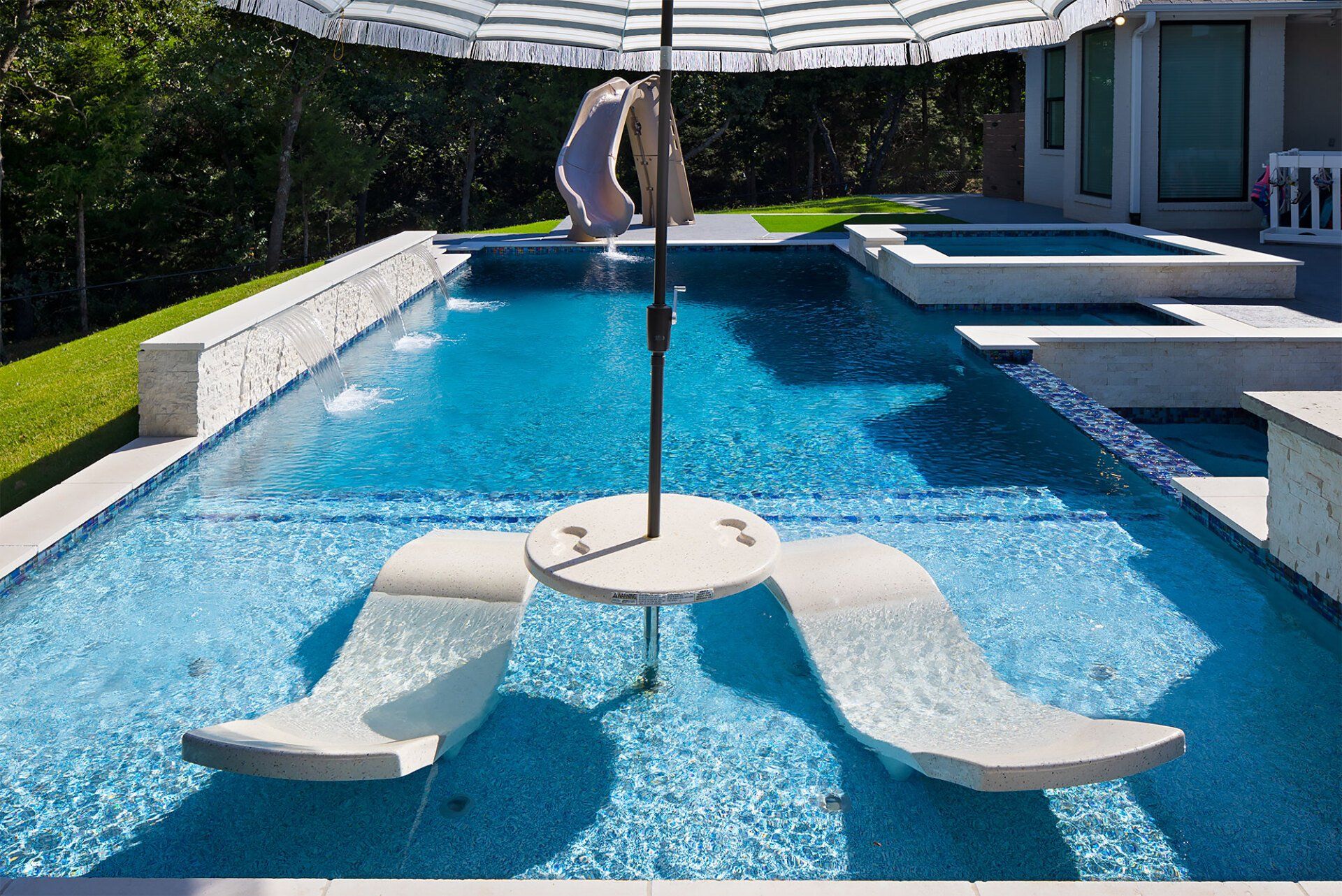 A swimming pool with a table and chairs under an umbrella