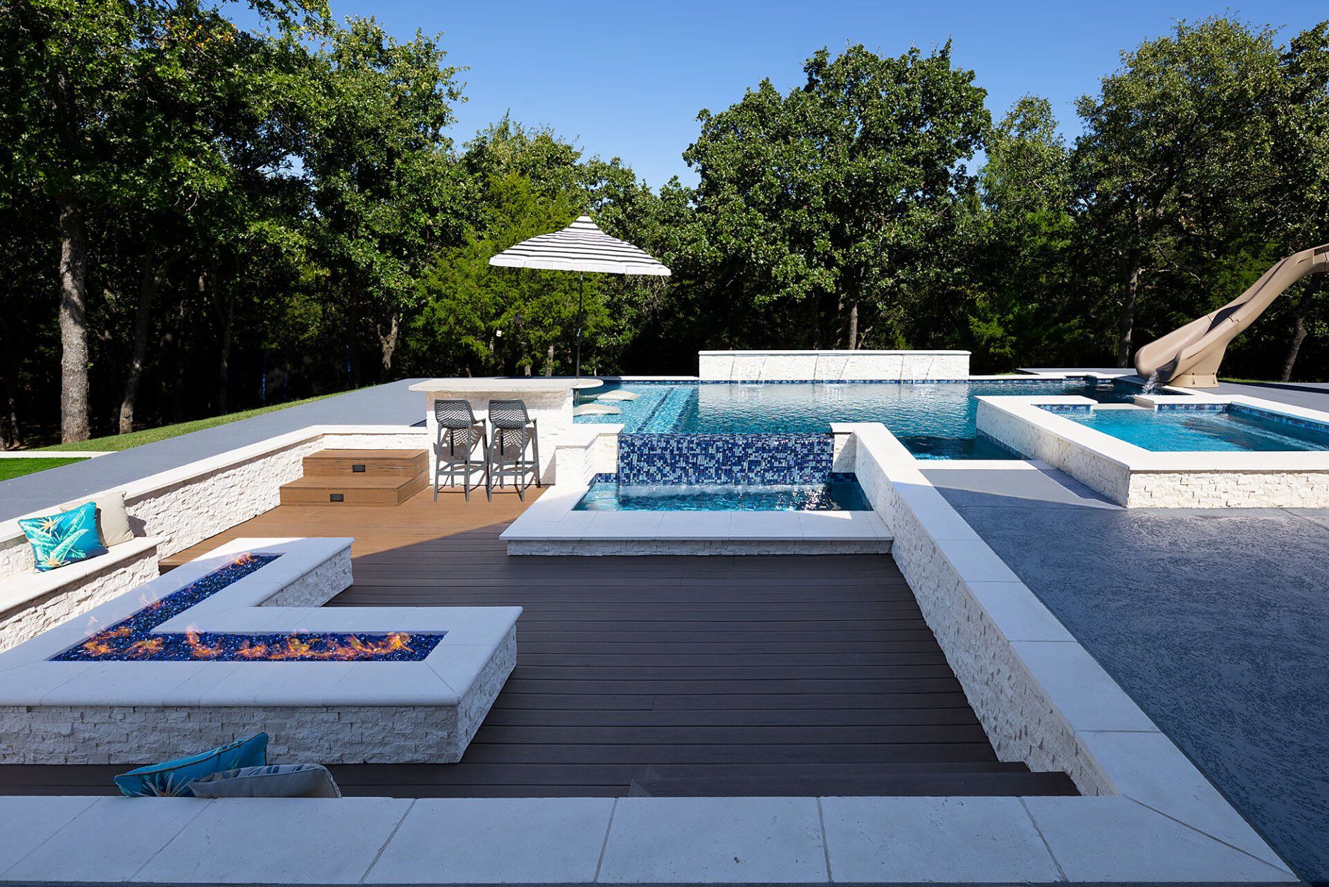 A large swimming pool with a slide and a fire pit