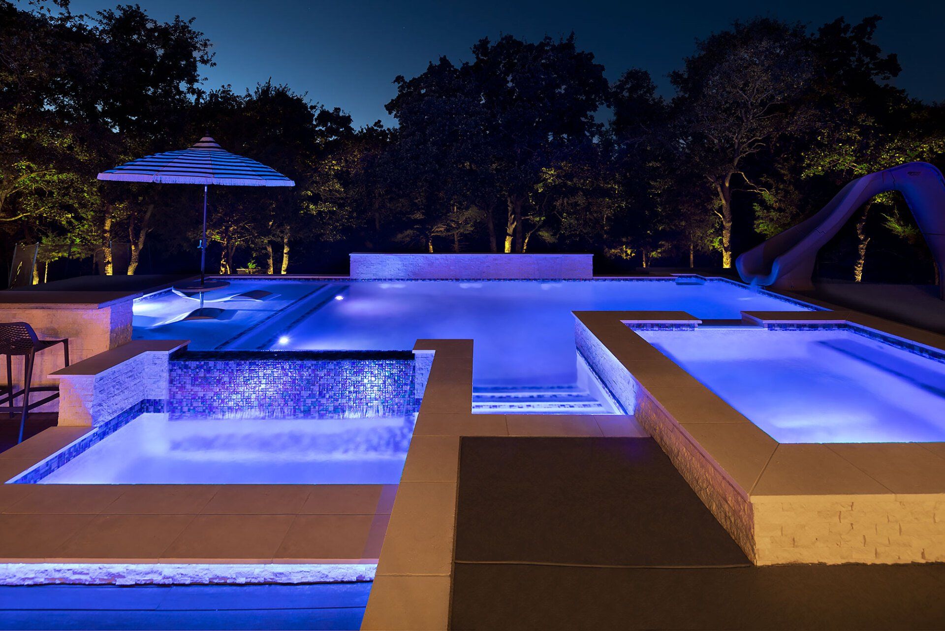 A large swimming pool is lit up at night