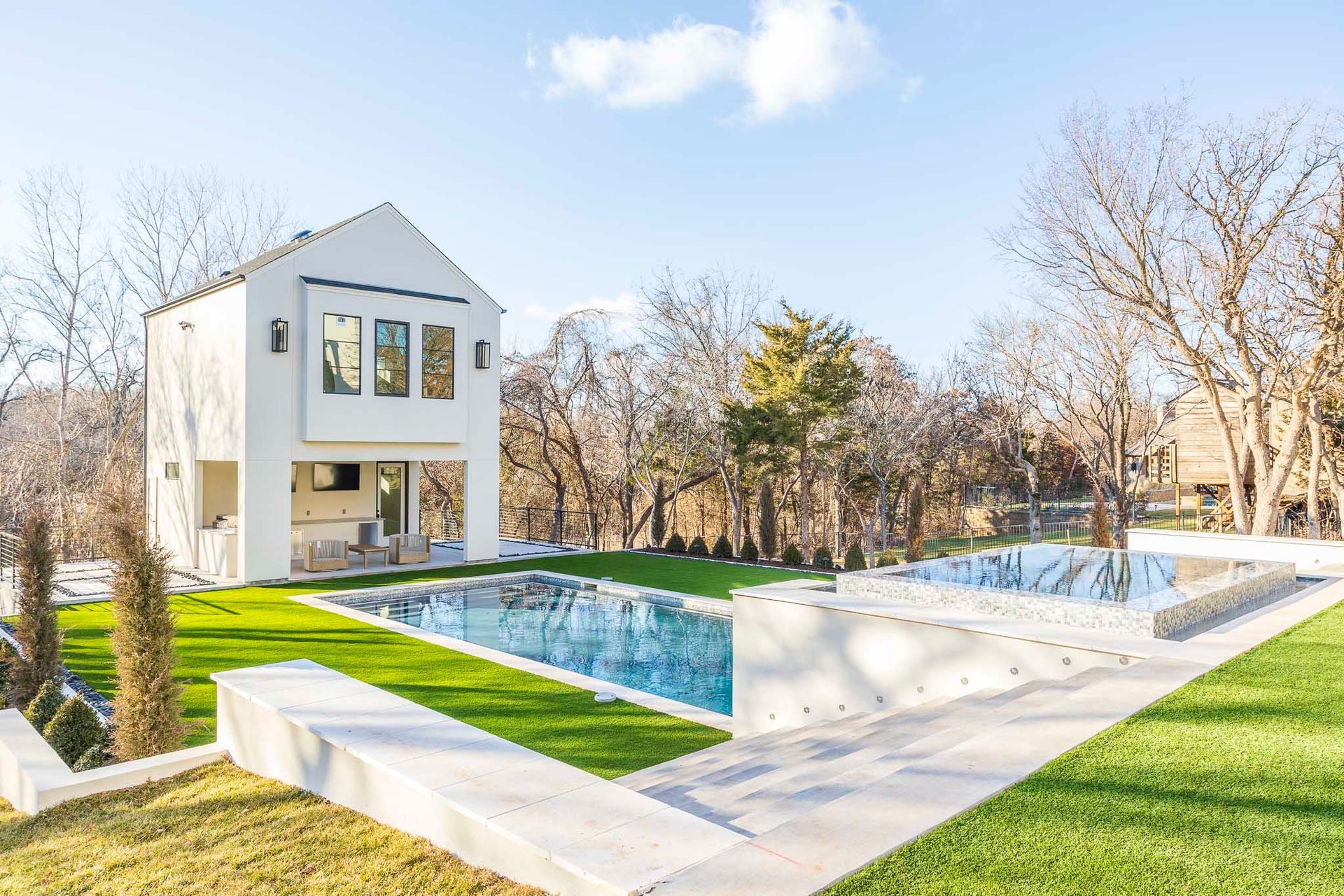 A white house with a large swimming pool in the backyard.