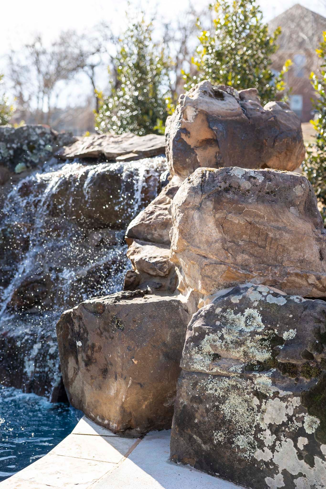 A waterfall is surrounded by rocks next to a pool.