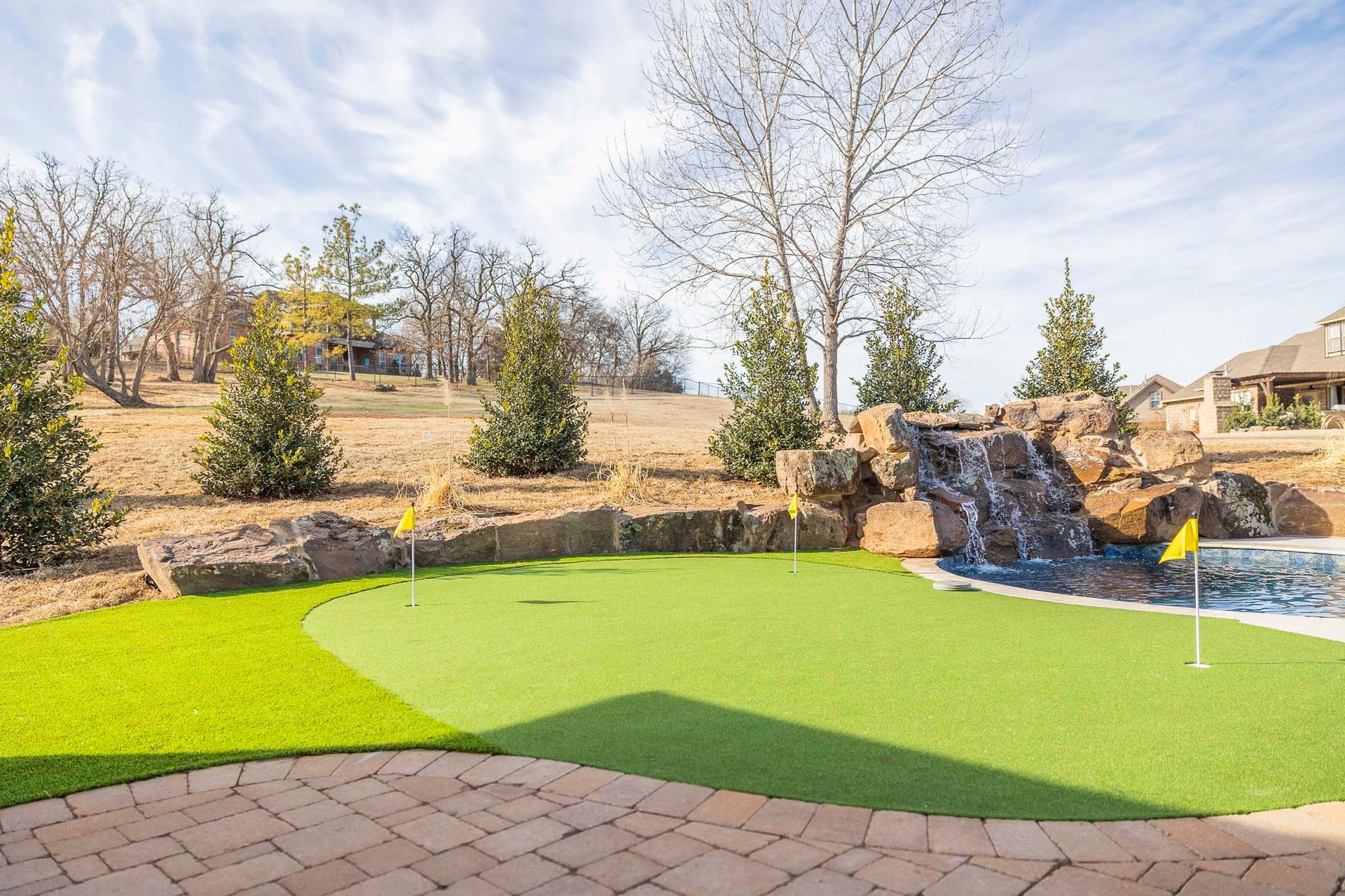 There is a waterfall in the background of the putting green.