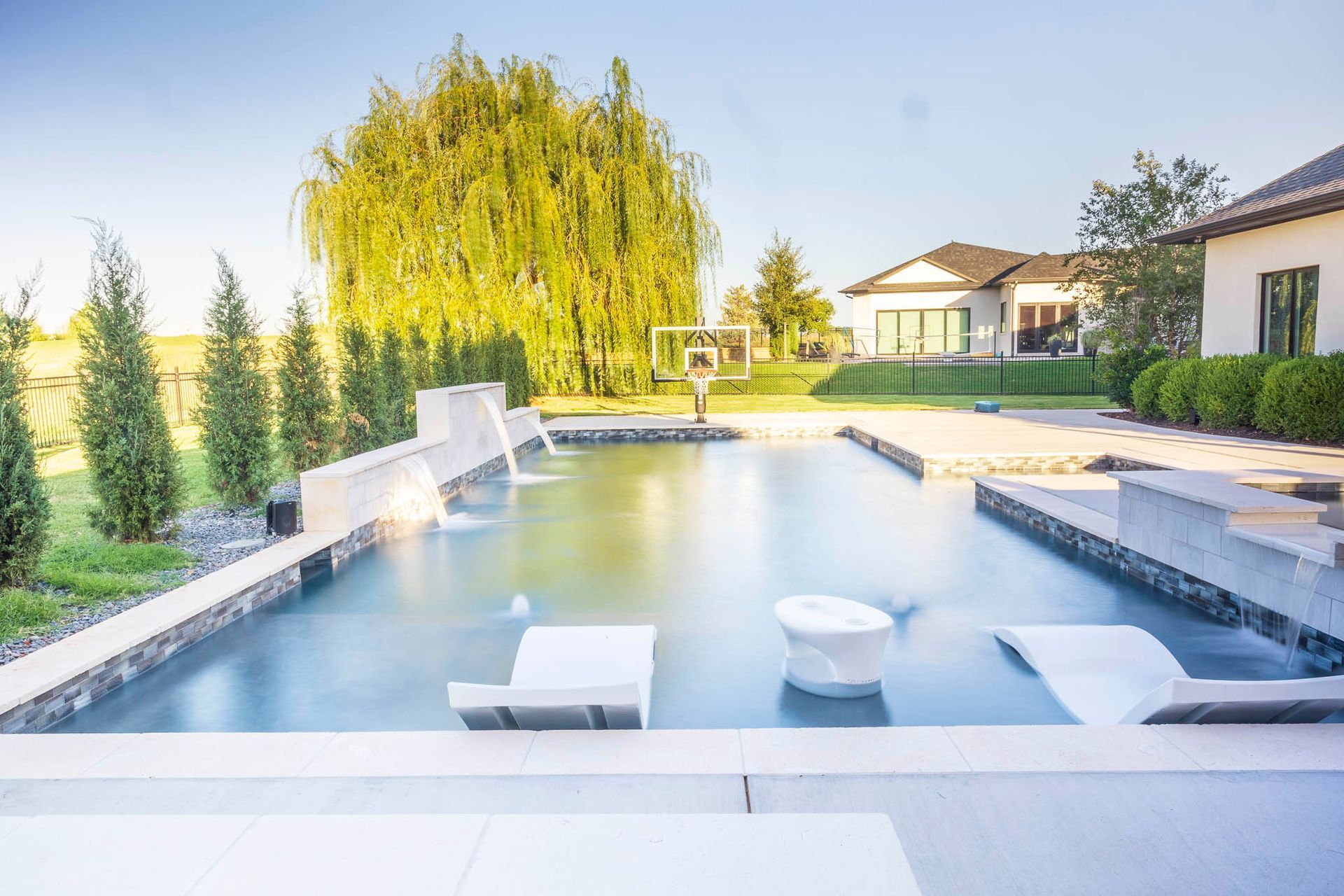 There is a large swimming pool in the backyard of a house.
