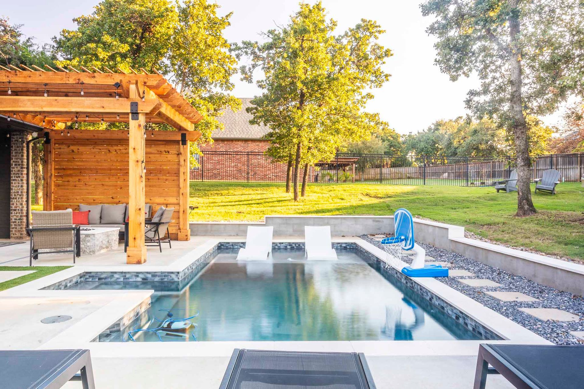 There is a large swimming pool in the backyard with a pergola.