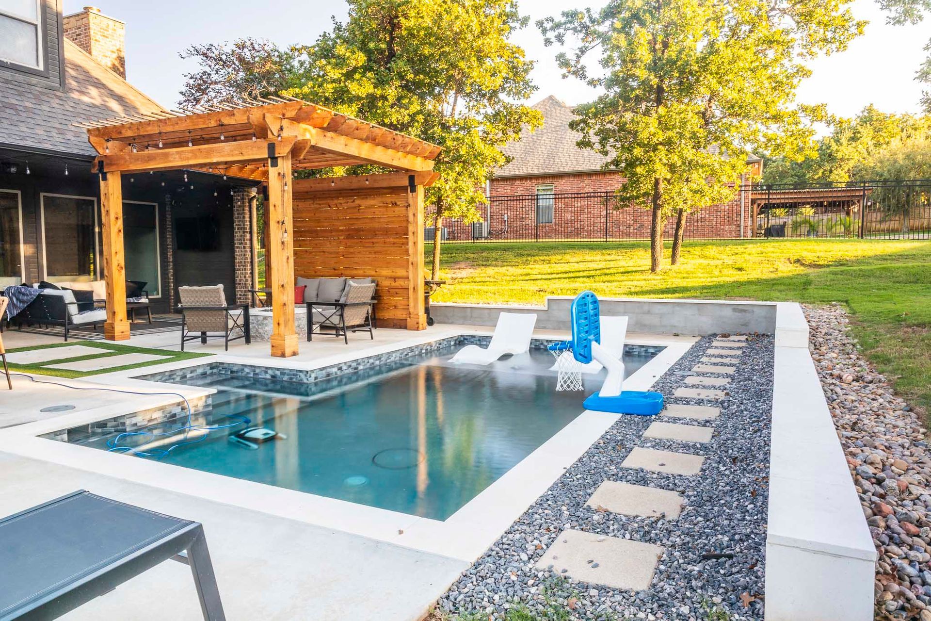 A large swimming pool with a pergola in the backyard of a house.