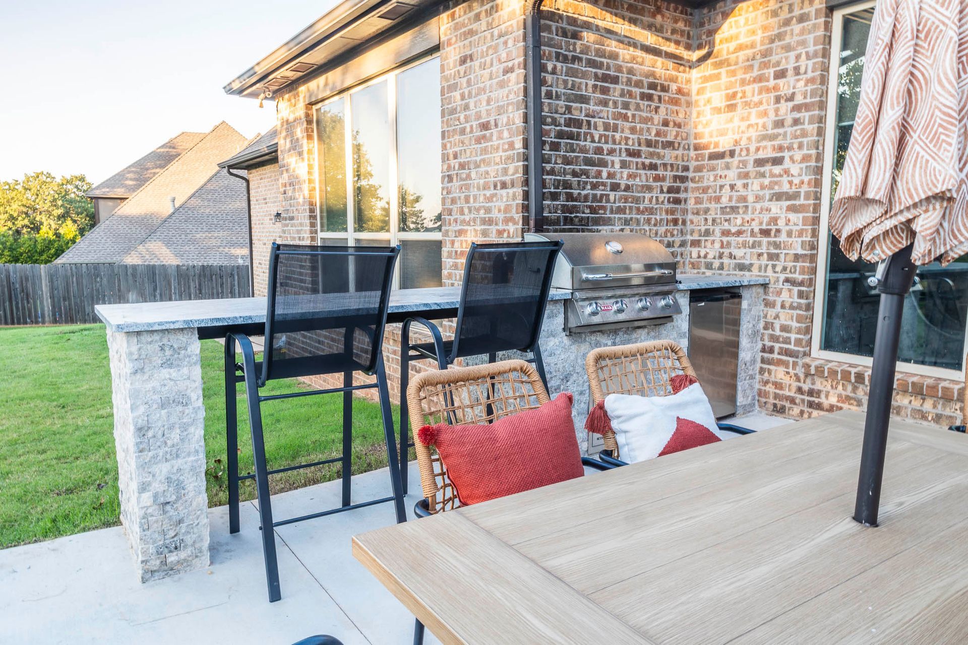 A patio with a table and chairs and a grill.