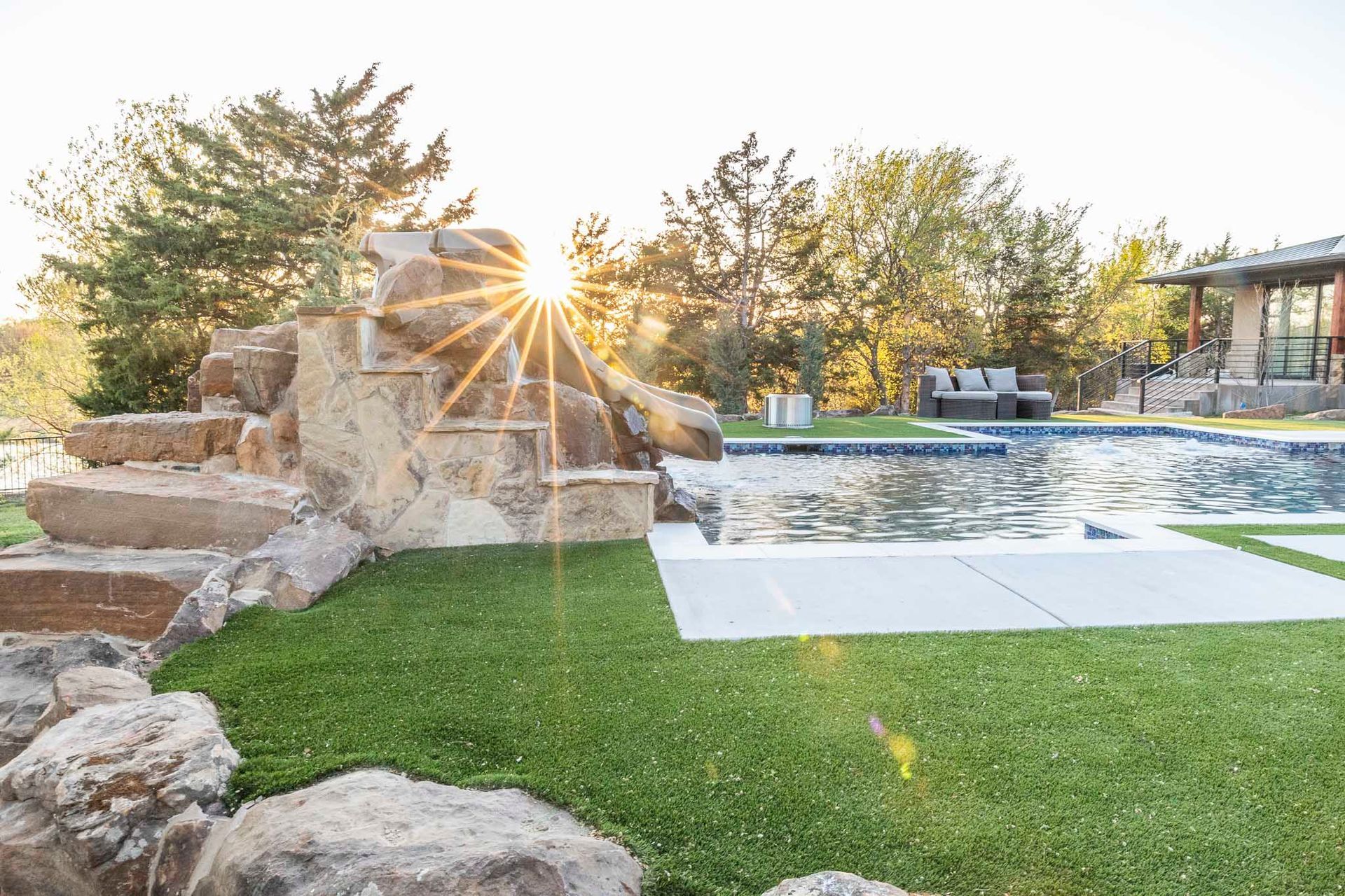 A large swimming pool with a waterfall in the backyard of a house.