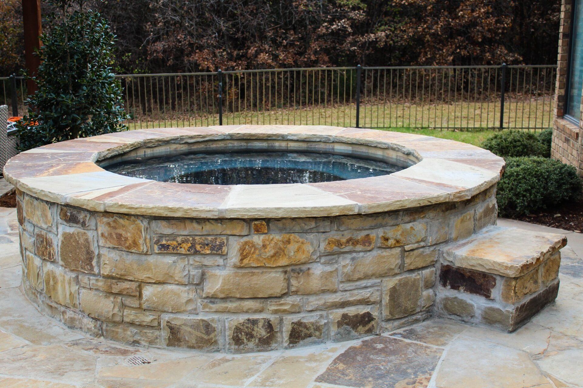 A stone hot tub is sitting on top of a stone patio.