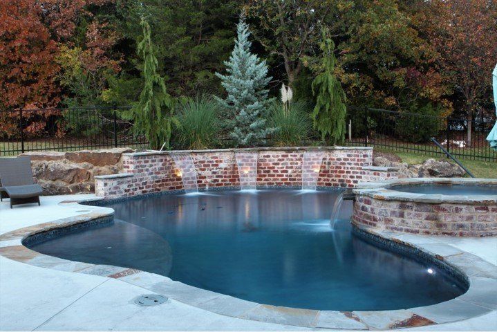 A large swimming pool with a waterfall in the backyard