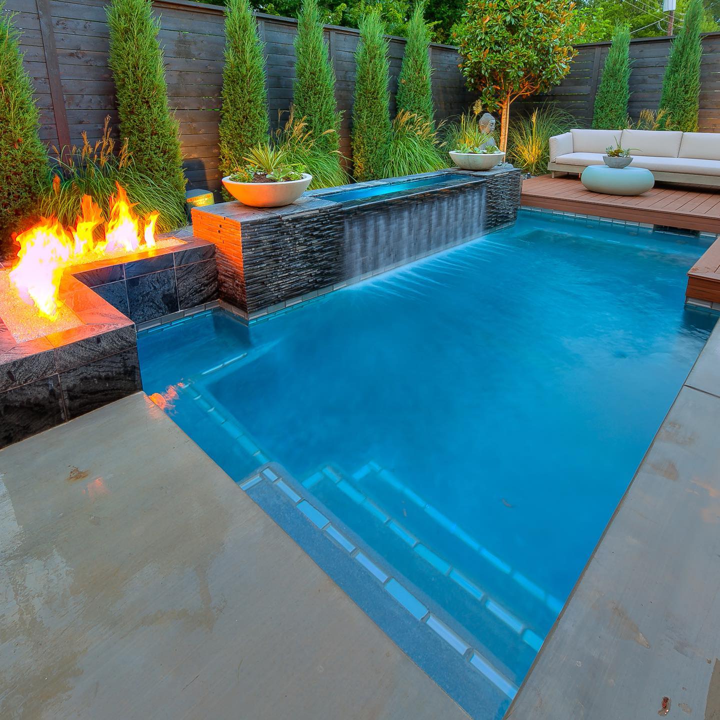 A swimming pool with a waterfall and a fire pit