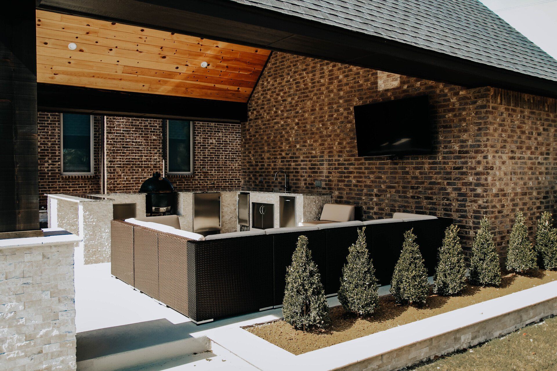 A brick house with a patio area with furniture and a television.