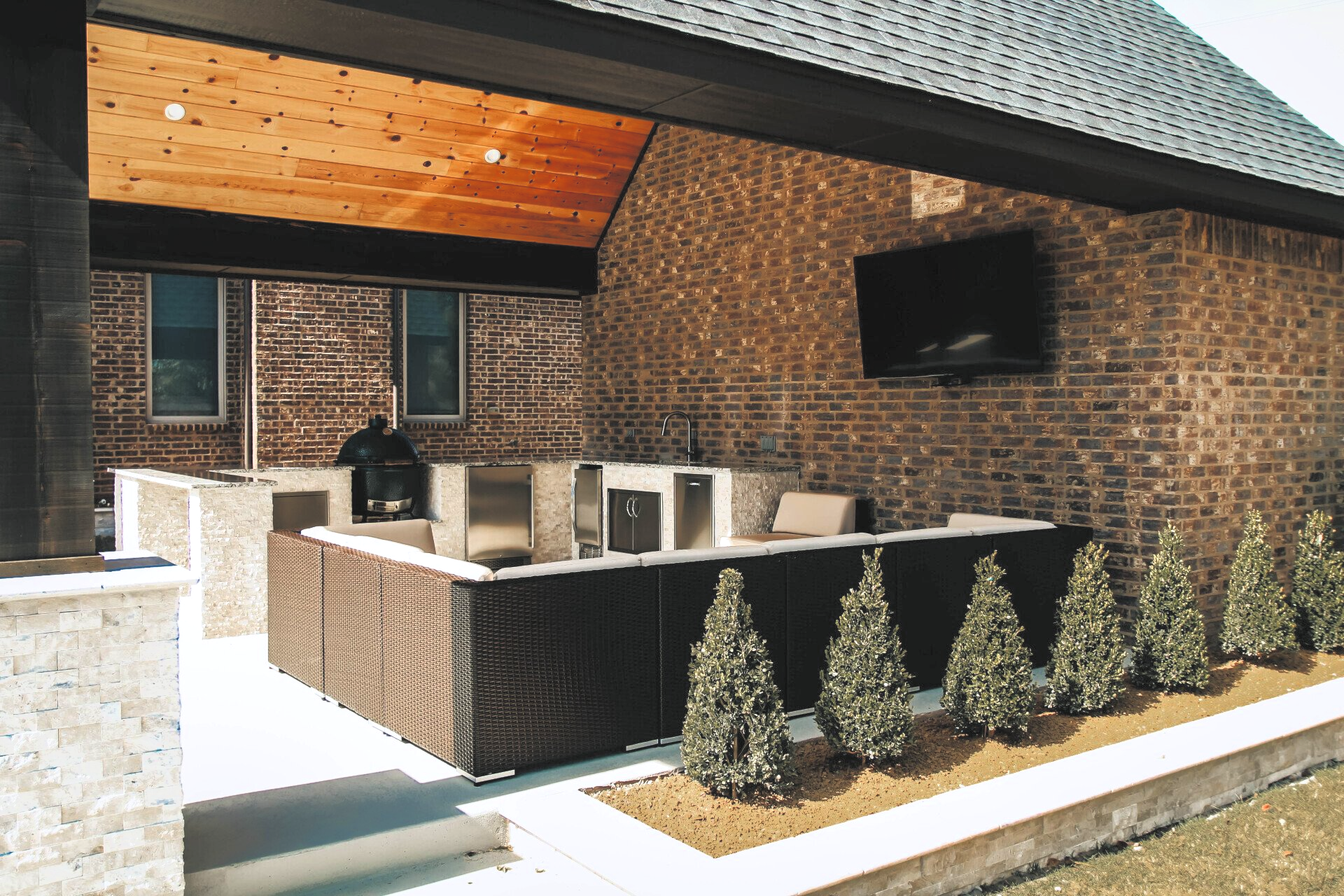 A brick house with a patio area with furniture and a television.