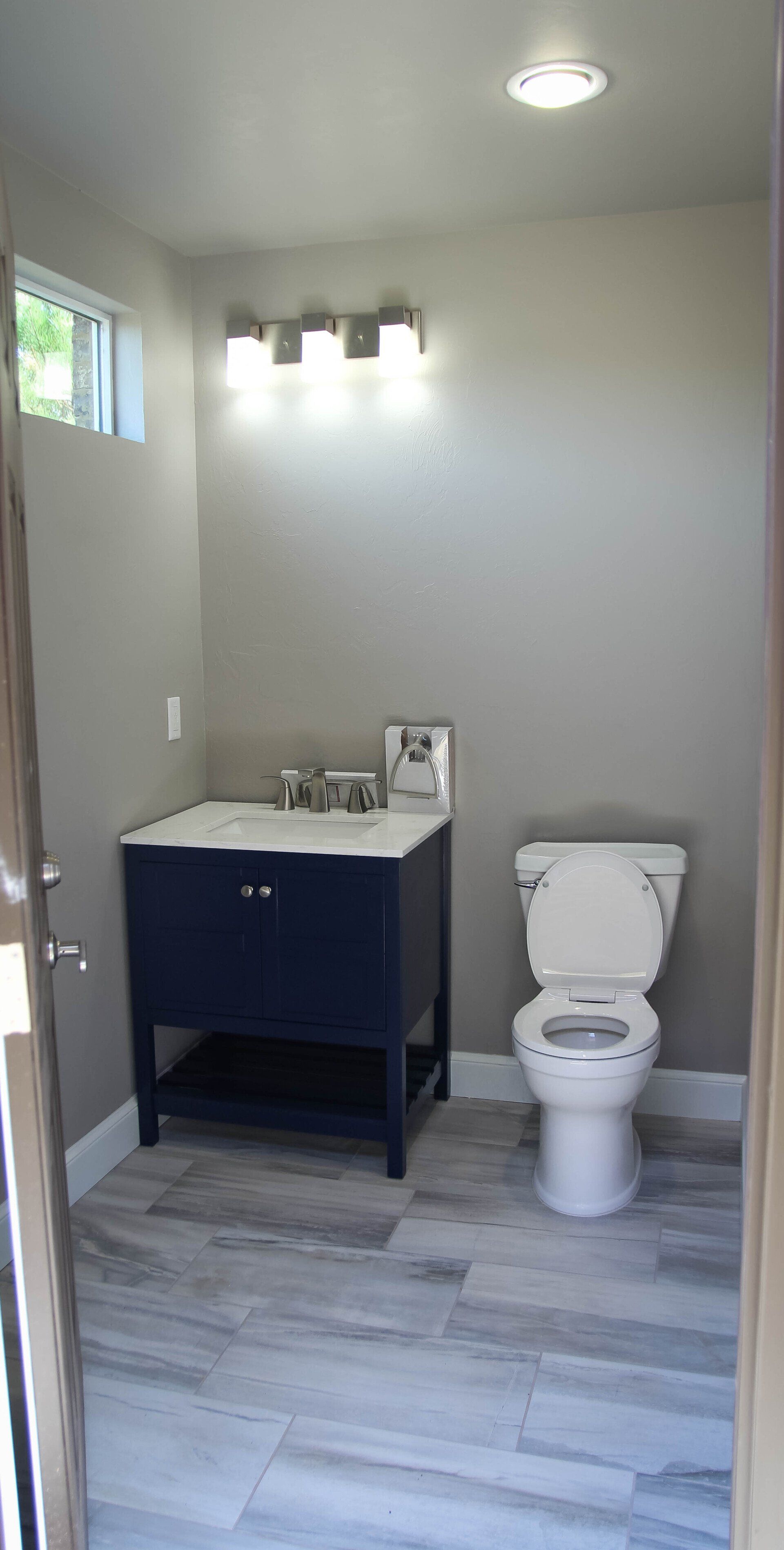 A bathroom with a toilet , sink and mirror.