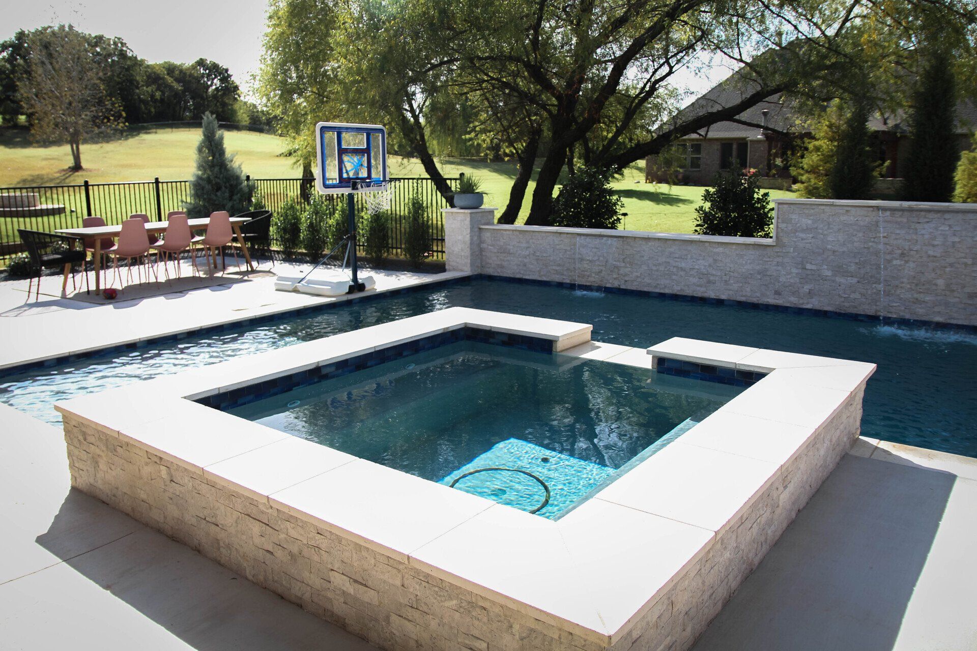 A large swimming pool with a basketball hoop in the backyard