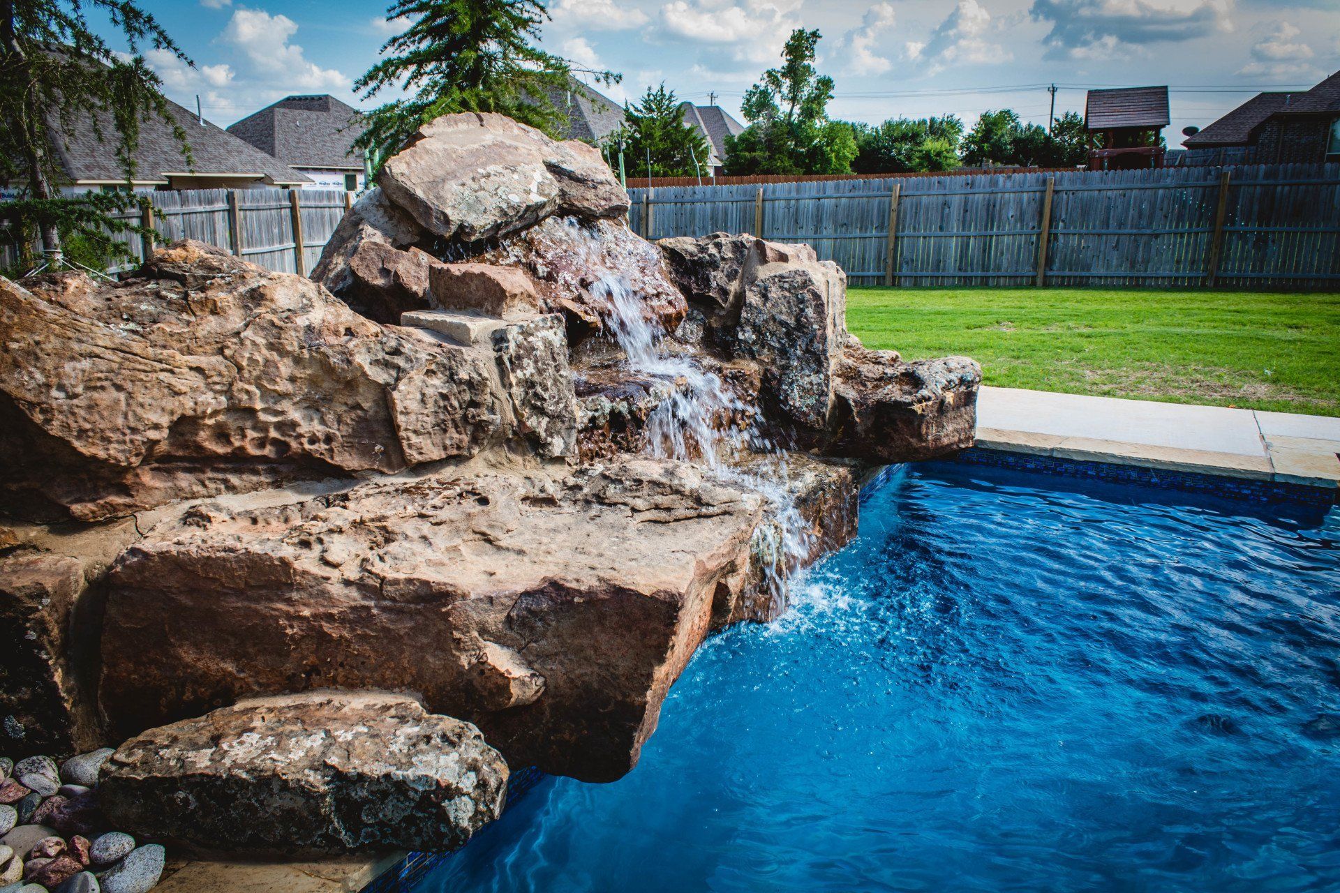 There is a waterfall in the middle of a swimming pool.