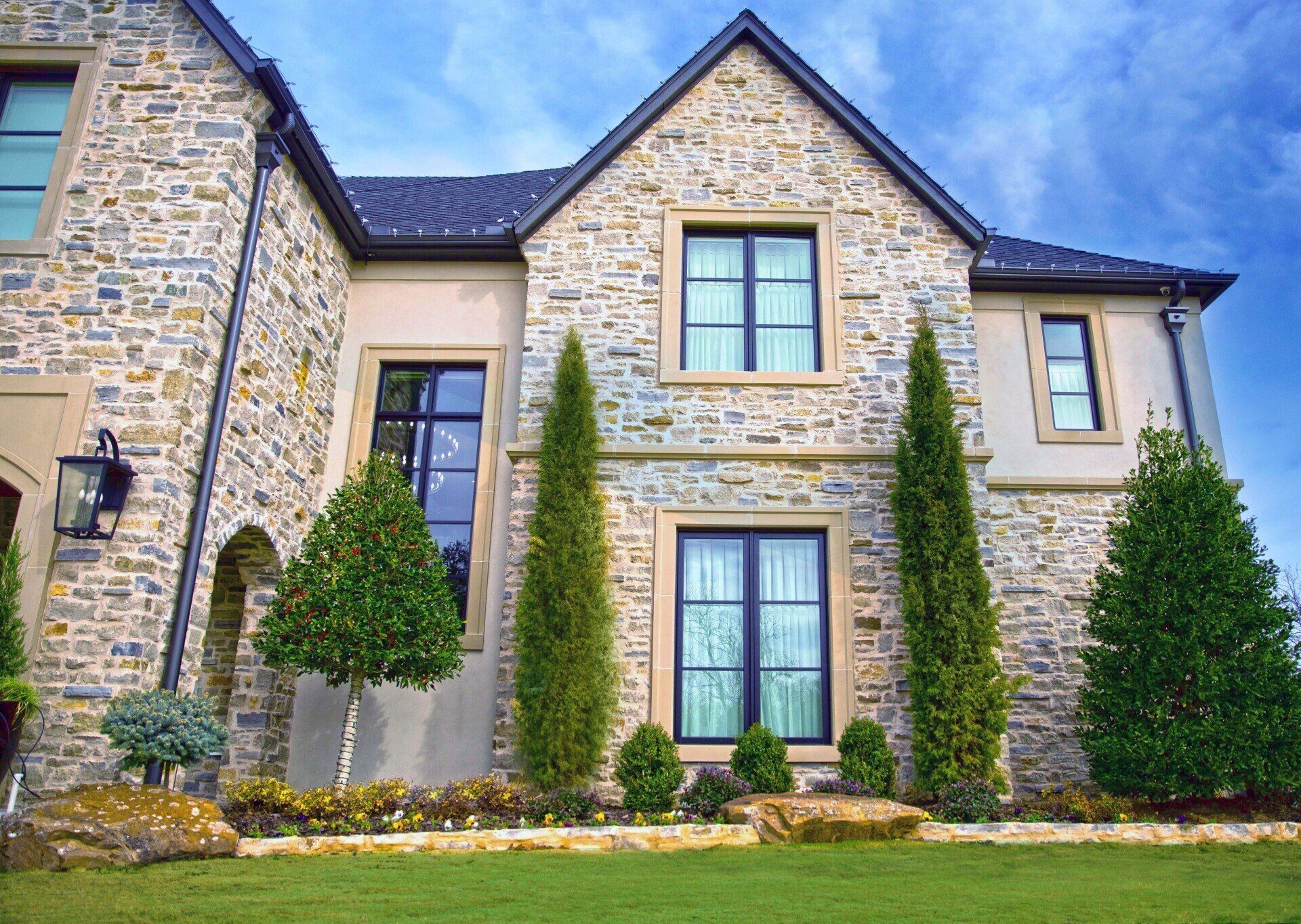 A large stone house with a lot of windows and trees in front of it