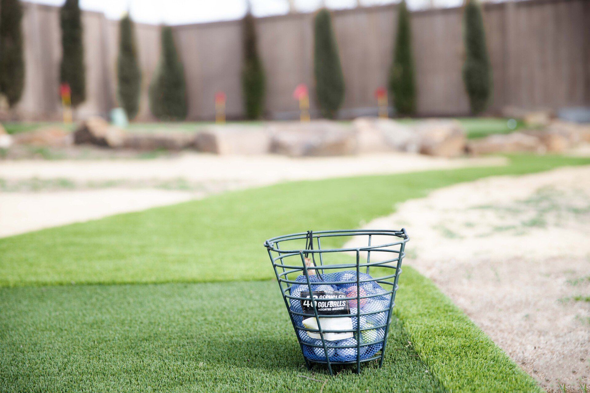 A basket filled with golf balls is sitting on top of a lush green field.