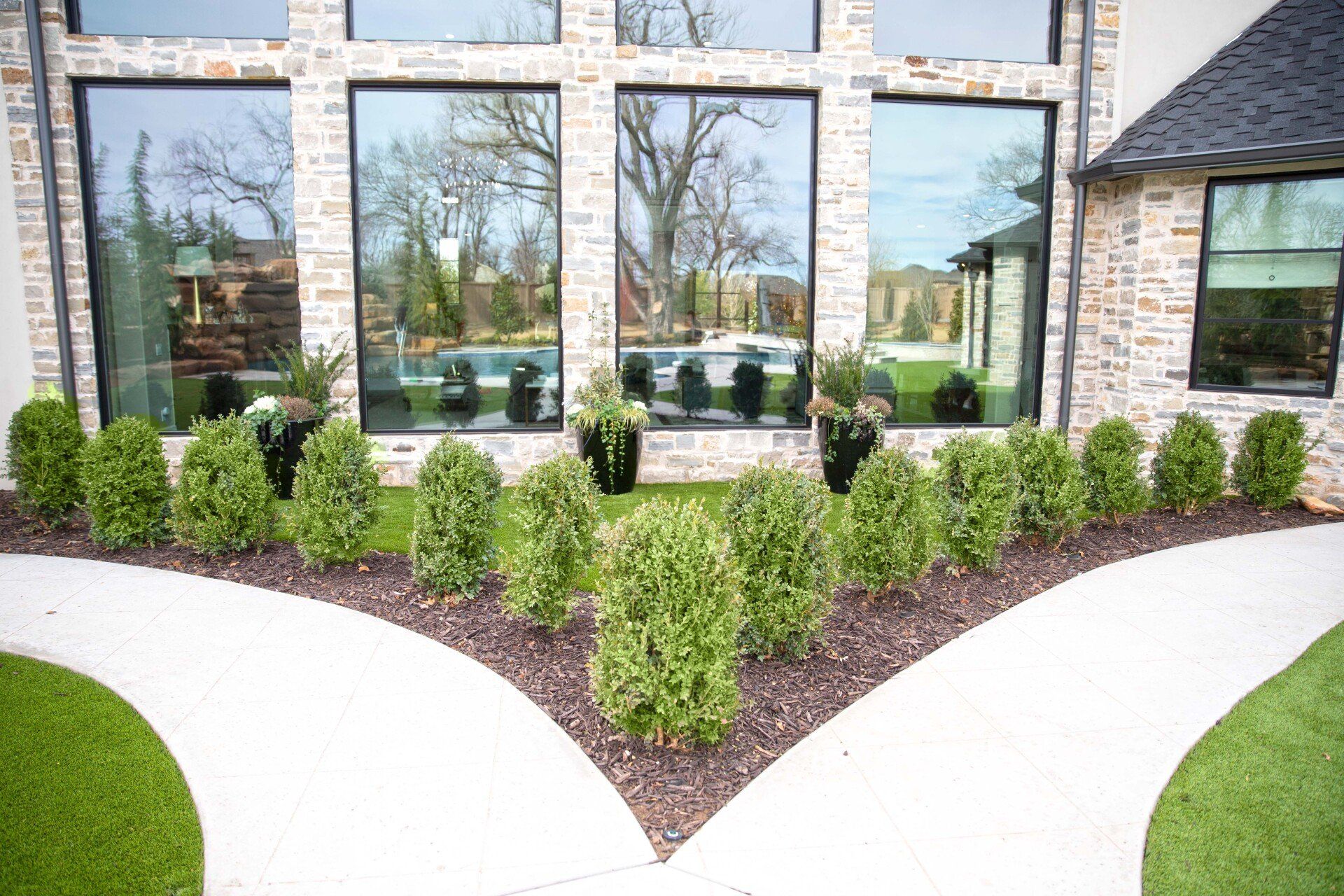 A house with a lot of windows and bushes in front of it