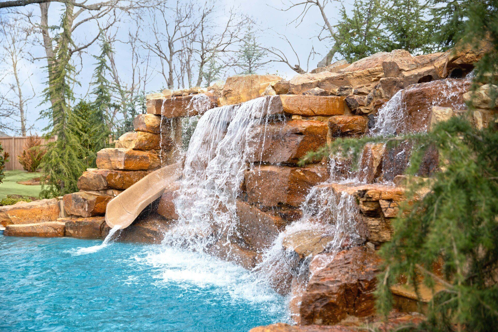There is a waterfall in the middle of a swimming pool.