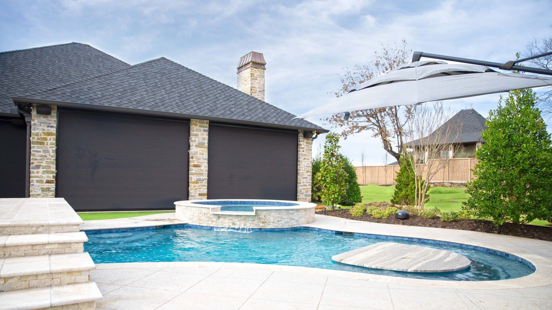 There is a large swimming pool in the backyard of a house.