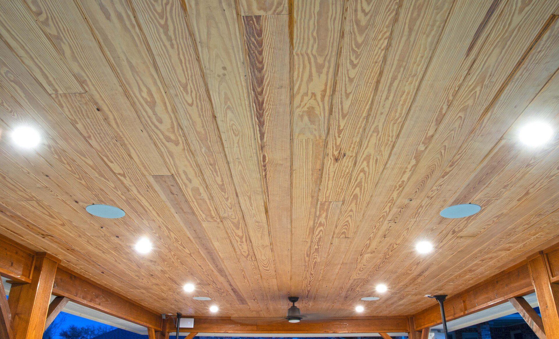 A wooden ceiling with a ceiling fan and lights.