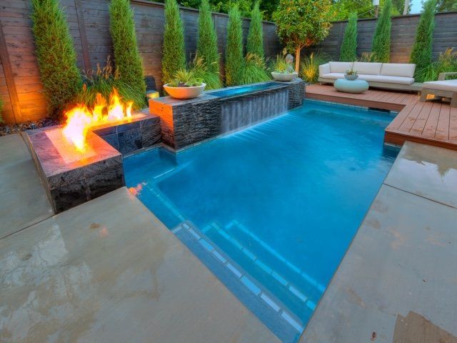 A swimming pool with a waterfall and a fire pit