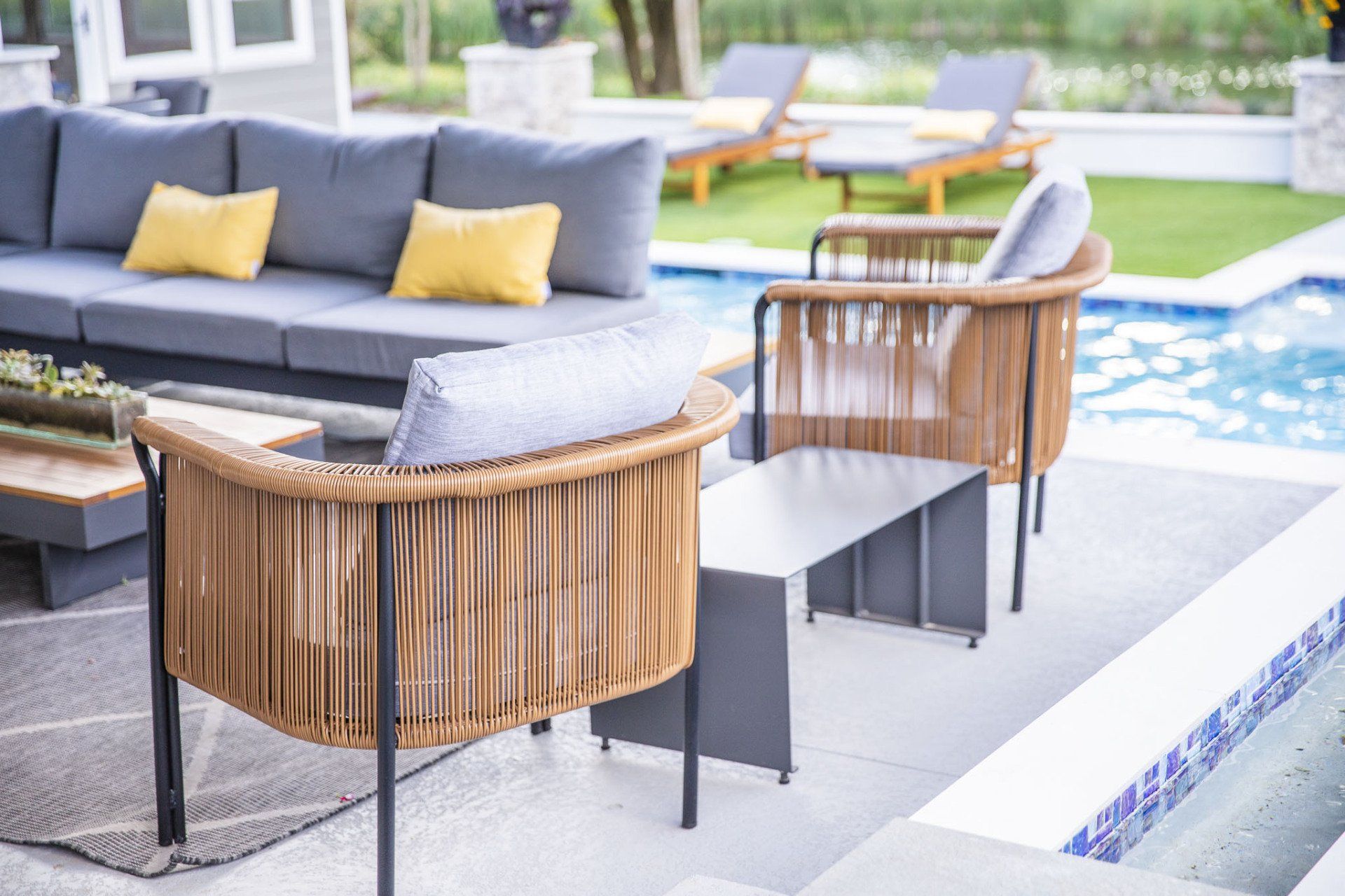 A patio with a couch and chairs next to a pool.