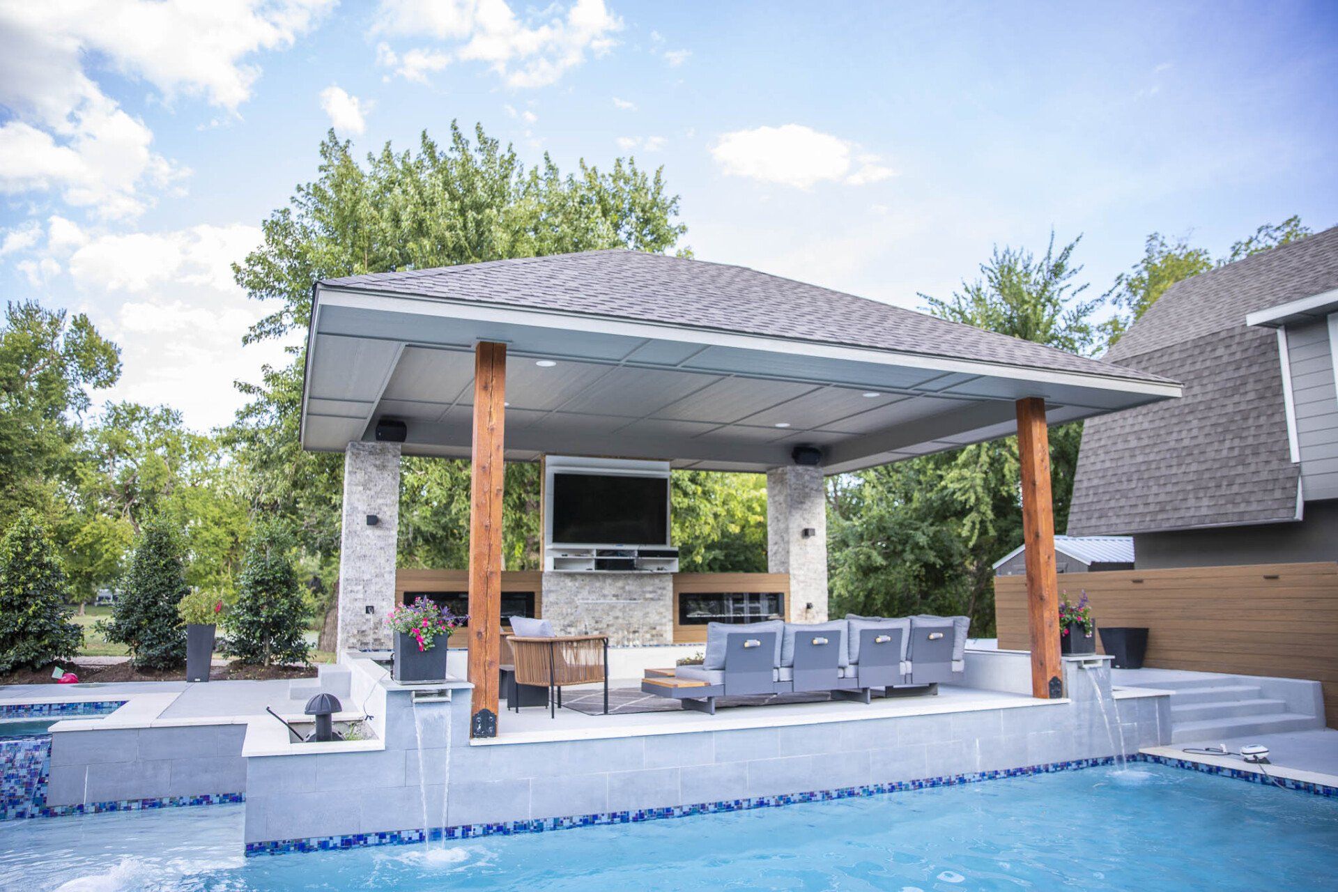 A large swimming pool with a pavilion and a television above it.