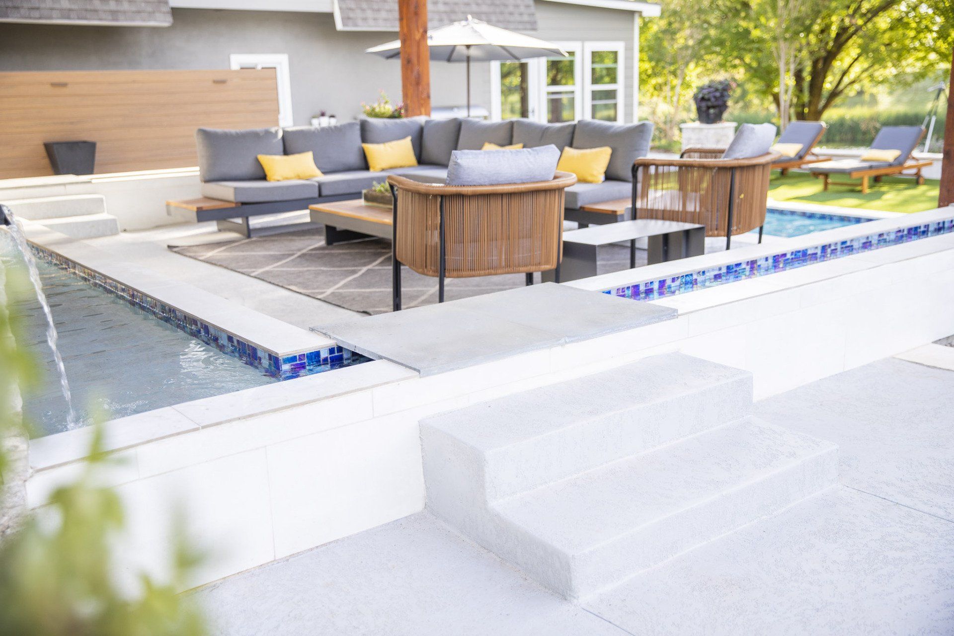 A patio with a couch and chairs next to a pool.