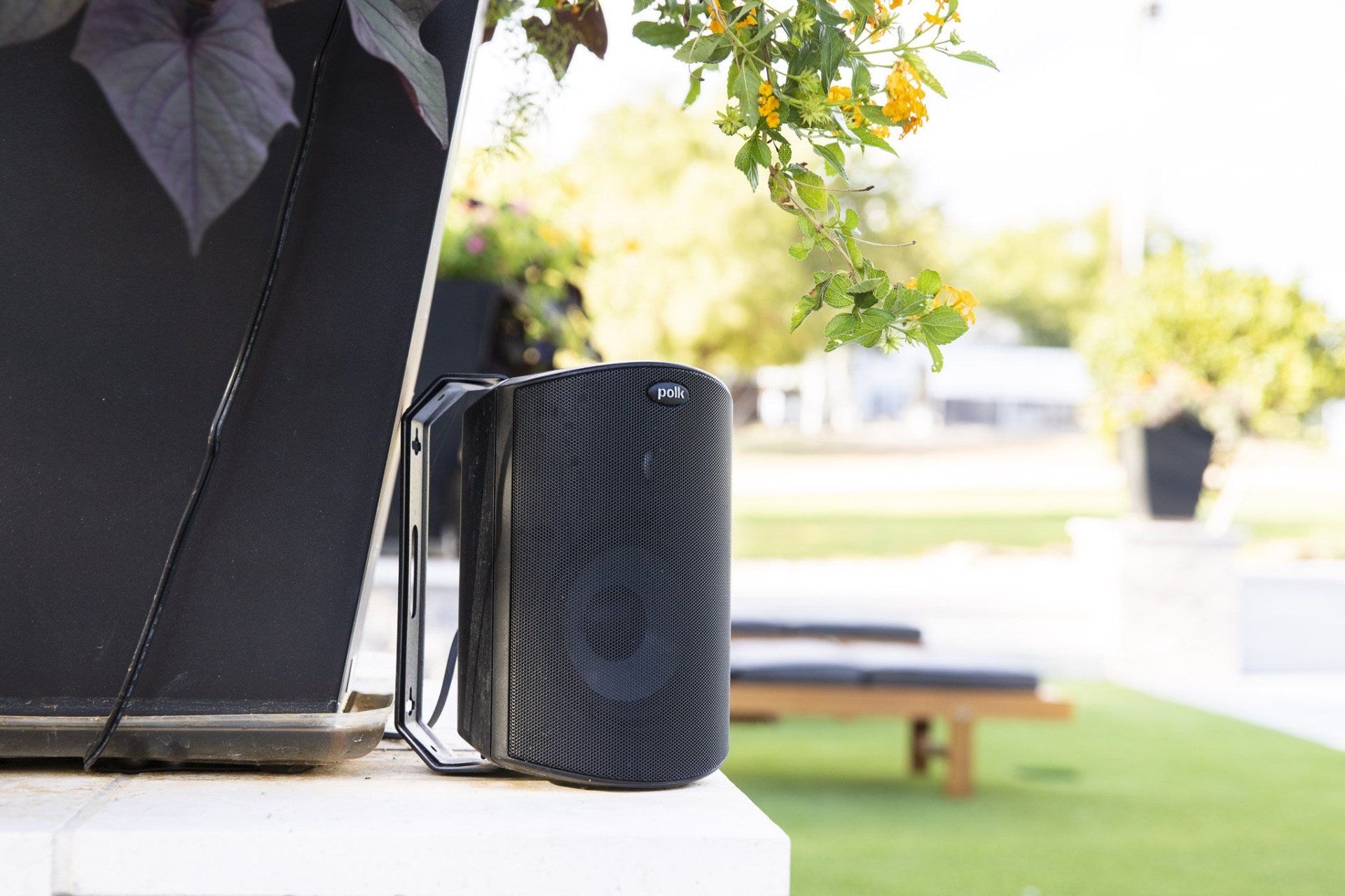 A speaker is sitting next to a laptop on a table.