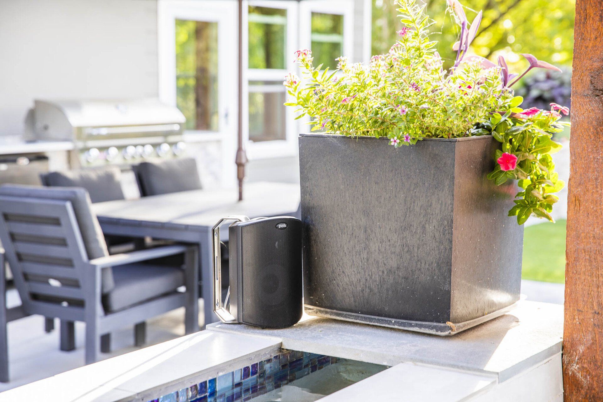 A planter with flowers in it is sitting next to a pool.